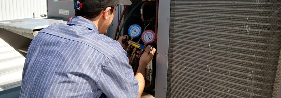 HVAC technician servicing a condenser unit in Elk Plain